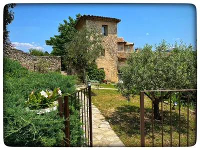 an old stone building with a gate in a garden at La Providence in Apt