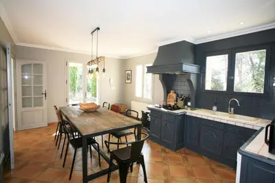 a kitchen with a wooden table and a dining room at le jas de Saint Hilaire in Ménerbes