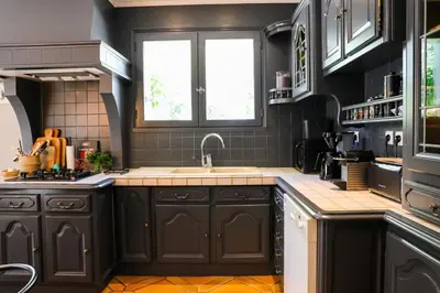 a kitchen with black cabinets and a sink at le jas de Saint Hilaire in Ménerbes
