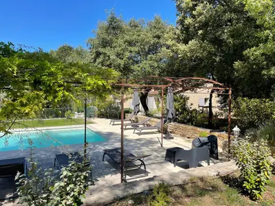 a pool with a pergola and chairs next to a pool at le jas de Saint Hilaire in Ménerbes