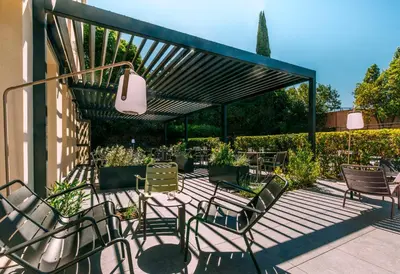 acovered patio with chairs and tables and awning at Escale Oceania Aix-en-Provence in Aix-en-Provence