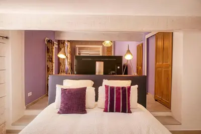 a bedroom with a large bed with purple walls at Le Hameau Fleur de Pierres , Chambre , Gite et Table d'Hôtes in Murs