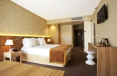 a hotel room with a bed and a flat screen tv at Golden Tulip Avignon Le Paradou in Avignon