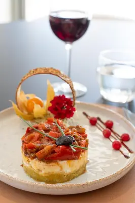 a plate with a piece of food on a table with a wine glass at Golden Tulip Avignon Le Paradou in Avignon