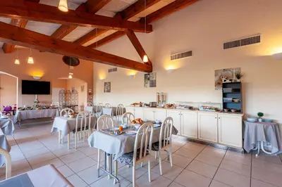 a restaurant with tables and chairs and a kitchen at Residhotel Golf Grand Avignon in Vedène