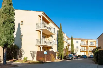 a building with balconies and cars parked on a street at Residhotel Golf Grand Avignon in Vedène