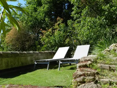 two white chairs sitting in the grass near a fence at Les Acanthes in Lauris