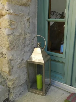 a lantern with a green candle in front of a door at Les Acanthes in Lauris