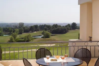 a table and chairs on a balcony with a view at Madame Vacances Résidence Provence Country Club in Saumane-de-Vaucluse