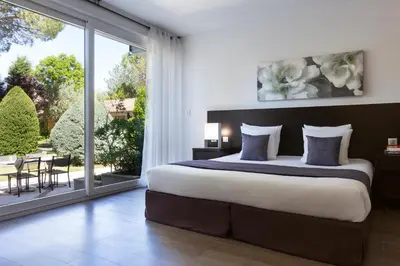 a bedroom with a large bed and a large window at SOWELL HOTELS Domaine de la Petite Isle in LʼIsle-sur-la-Sorgue