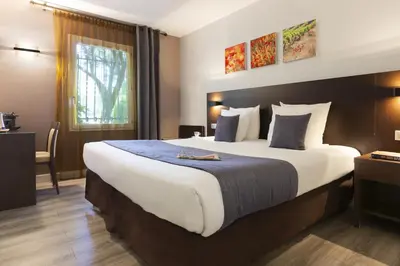 a hotel room with a large bed and a window at SOWELL HOTELS Domaine de la Petite Isle in LʼIsle-sur-la-Sorgue