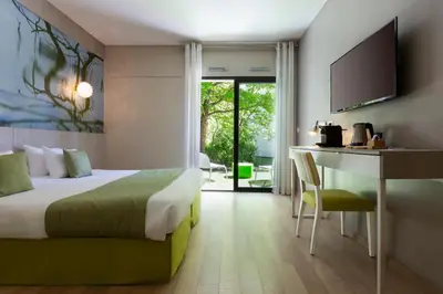 a hotel room with a bed and a desk and a kitchen at SOWELL HOTELS Domaine de la Petite Isle in LʼIsle-sur-la-Sorgue