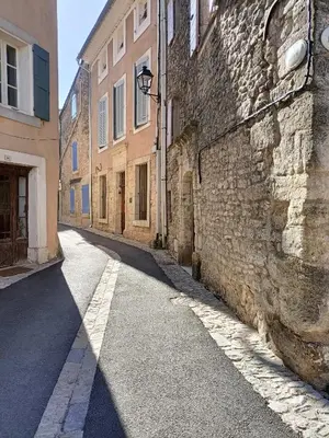 an alley with a stone wall and a building at Fenêtre sur vue in Saignon