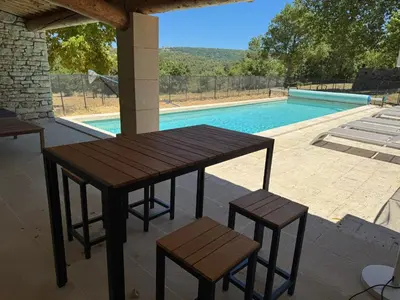 a wooden table and chairs next to a swimming pool at Villa spacieuse avec jardin à Saignon in Saignon