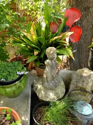 a statue sitting next to some plants in a garden at Villa - La quiétude de St Antoine - piscine privée in LʼIsle-sur-la-Sorgue