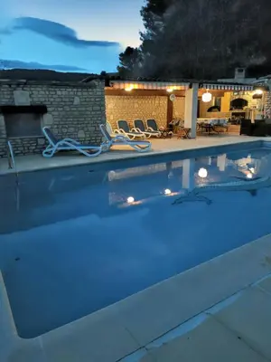 a swimming pool with two lounge chairs in it at night at Villa spacieuse à Lioux avec piscine privée et vue montagne in Lioux