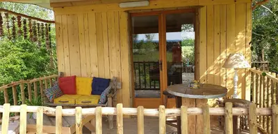 a porch of a wooden cabin with a chair and a table at LA CABANE PERCHEE in Villelaure