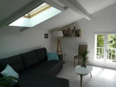 a living room with a black couch and a window at Bleu de l'Isle in LʼIsle-sur-la-Sorgue