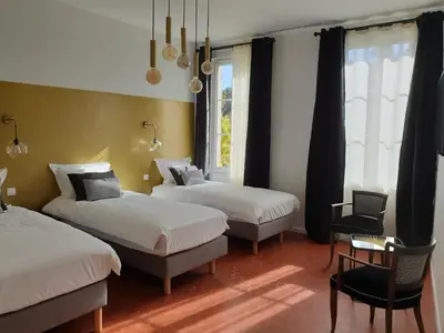 a bedroom with two beds and a chair and a window at Le Clos Marceau in Bédoin