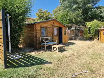 a small wooden cabin with a bench in the yard at Locations insolites 