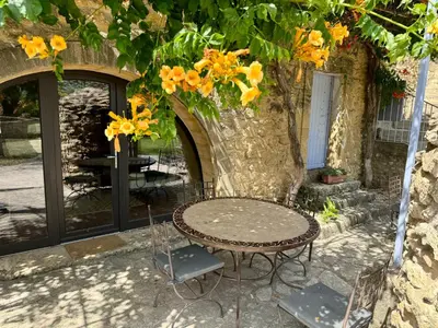 a table and chairs in front of a building with yellow flowers at Bastide du Buou in Puyvert