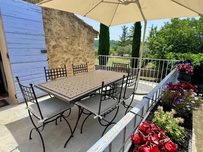 a table and chairs with an umbrella on a patio at Bastide du Buou in Puyvert