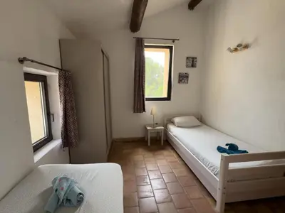 a small bedroom with two beds and a window at Bastide du Buou in Puyvert