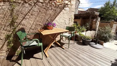 a wooden table and chairs on a wooden deck at Sous le Château in Rustrel