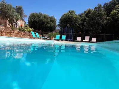 a swimming pool with blue chairs and water at l 'oliveraie in Gordes