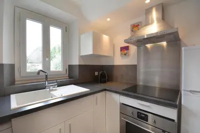 a kitchen with white cabinets and a sink and a window at l 'oliveraie in Gordes