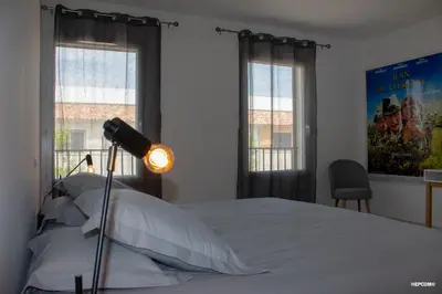 a bedroom with a bed with a lamp and windows at BASTIDE 9 in La Fare-les-Oliviers