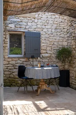 a table and two chairs in front of a stone wall at Mas OREA in Gordes