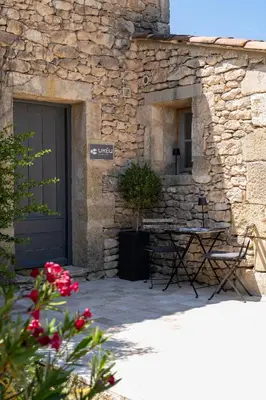 a stone building with a table in front of a door at Mas OREA in Gordes