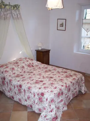 a bedroom with a bed with a red flowered blanket at La Bastide de Ninou maison de vacances Luberon in Viens