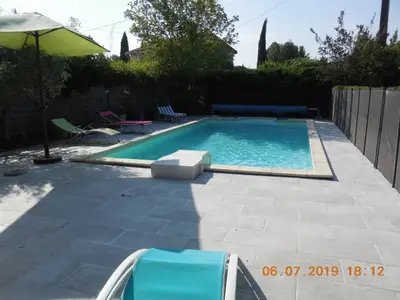 a swimming pool with two chairs and an umbrella at La maison bleue in LʼIsle-sur-la-Sorgue