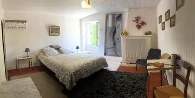 a bedroom with a bed and a table and a window at Charmante maison de village à Fontaine-de-Vaucluse in Fontaine-de-Vaucluse