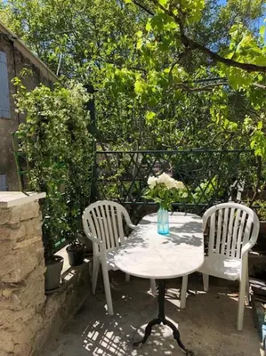 a table with two chairs and a vase on it at Charmante maison de village à Fontaine-de-Vaucluse in Fontaine-de-Vaucluse