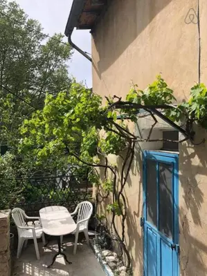 a table and chairs next to a building with a blue door at Charmante maison de village à Fontaine-de-Vaucluse in Fontaine-de-Vaucluse