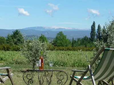 a table with a bottle of wine and two chairs at La Magnanerie in Bonnieux