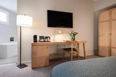 a bedroom with a desk with a television on the wall at Hôtel Boutique Cézanne centre Aix-en-Provence in Aix-en-Provence