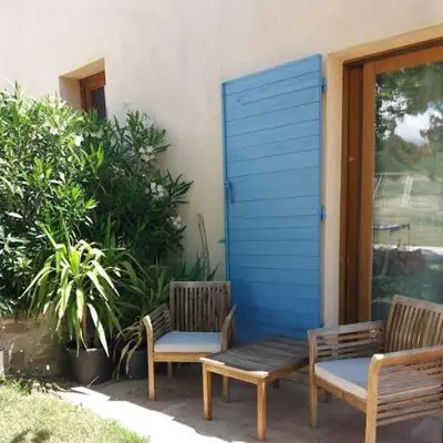 two benches sitting next to a building with a blue shutter at Domaine de la Marie dans le Luberon in Peypin-dʼAigues