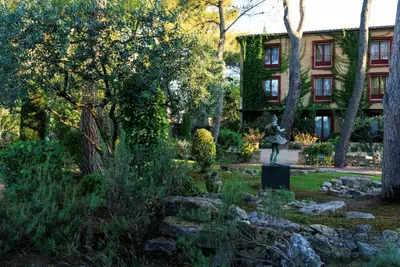 a garden with a statue in front of a building at Le Pigonnet - Esprit de France in Aix-en-Provence