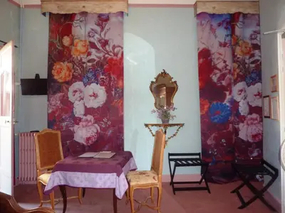 a room with a table and chairs and a wall with flowers at Hôtel du Fiacre in Carpentras