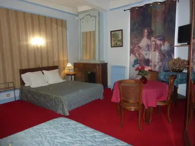 a hotel room with a bed and a table at Hôtel du Fiacre in Carpentras