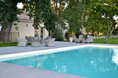 a swimming pool with lounge chairs and a house at Mas Le 7 in Saint-Andiol