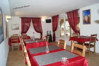 a dining room with red clothed tables and chairs at Le Mas des Chênes in Rognes