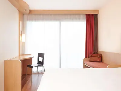 a hotel room with a bed and a chair and a window at Ibis Cavaillon Portes du Luberon in Cavaillon
