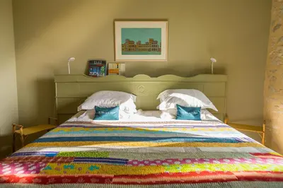 a bedroom with a large bed with a colorful quilt at Le Mas de la Sorgue in Le Thor
