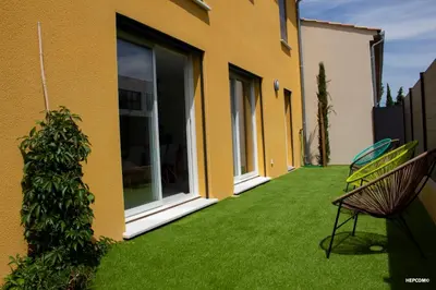 a yard with green grass and a yellow house at BASTIDE 7 in La Fare-les-Oliviers