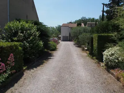 a gravel road in a garden with bushes and flowers at Une Heure Bleue in Manosque